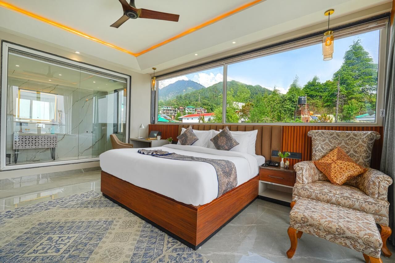 Une chambre avec un grand lit, une chaise, une table de chevet et une vue sur les montagnes.