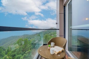 Un balcon avec un fauteuil en osier, une petite plante et un livre.