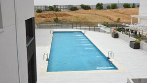 A rectangular swimming pool with a clear blue water surface, surrounded by a white tiled deck. - RivasCenter Apartment (Rivas-Vaciamadrid)