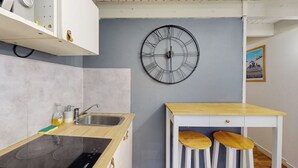 Une cuisine moderne équipée d’une cuisinière intégrée, d’un évier et d’une table en bois avec deux tabourets.
