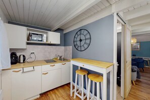 A compact kitchen with a microwave, coffee maker, and bar stools. - Charming one-bedroom apartment in downtown Nantes, near the tram and train station (Nantes)