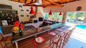 A modern kitchen with a central island, red pendant lights, and a brick oven.
