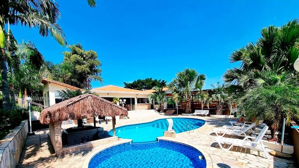 A swimming pool area with two pools, lounge chairs, and palm trees.