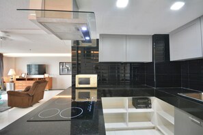 Eine moderne Küche mit schwarzem Arbeitsplatz, integriertem Mikrowellenofen und einer Glasrückwand.