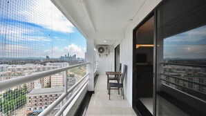 Een balkon met uitzicht op een stadsbeeld, een tafel met stoelen en een airconditioning.