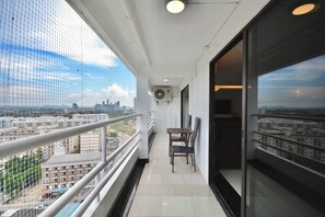 Ein Balkon mit Blick auf die Stadtlandschaft, ein Tisch mit Stühlen und eine Klimaanlage.