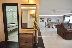 Eine moderne Hotelhalle mit einer Rezeption, einem großen Spiegel, einer Vase mit Blumen, einem Essbereich mit Stühlen und einem Tisch sowie einem Ledersofa.