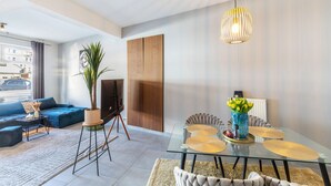 Un salon moderne comprenant un canapé, un téléviseur, une table à manger et des plantes décoratives.