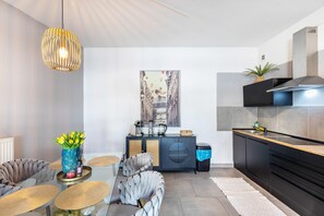 Una cocina moderna con encimera negra, estufa integrada y una lámpara colgante.