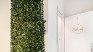 Un mur végétal vertical, une porte avec une pancarte indiquant « Bienvenue », et un interrupteur sur le mur.