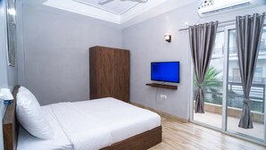 Una habitación de hotel moderna con una cama de madera, un televisor de pantalla plana y un balcón con cortinas.