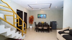 Una sala de estar moderna con una escalera, comedor y televisor de pantalla plana montado en la pared.