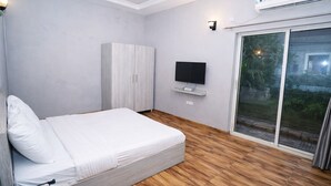 Un dormitorio con cama, armario, televisión y puerta corrediza de vidrio a un balcón.