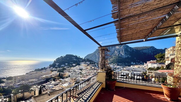 Una terraza con vistas a un pueblo costero, una montaña y el mar.
