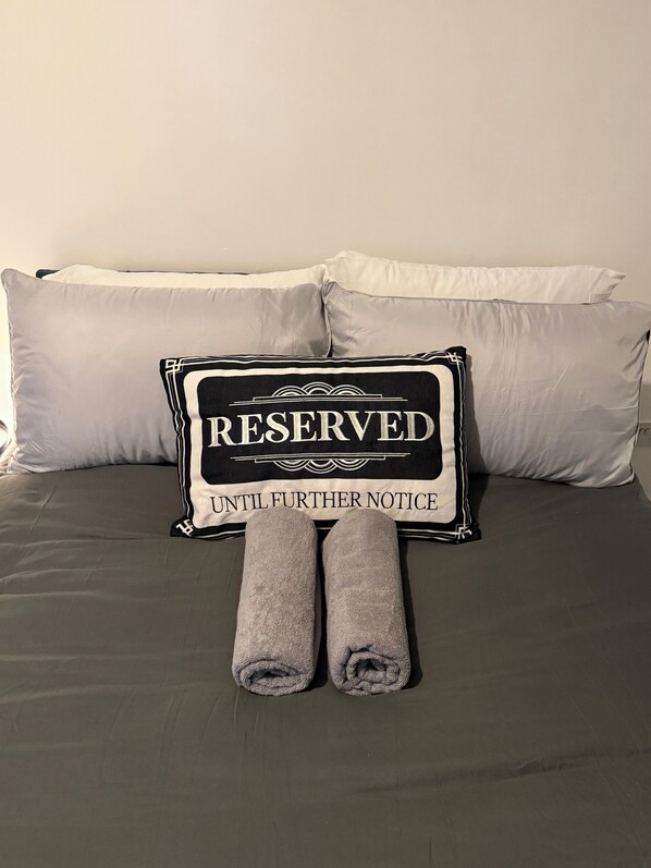 A bed with grey bedding, two pillows, and a sign reading "RESERVED UNTIL FURTHER NOTICE" placed on the bed. - The London Base Studio Apt – Finsbury Park (London)