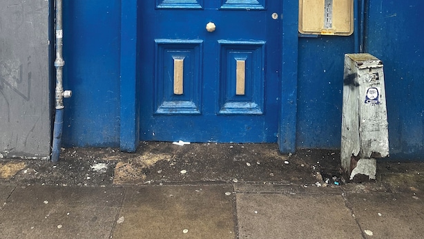 Puerta azul con los números 259 y 261, un teléfono y un rótula de emergencia.