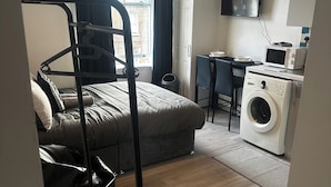 Habitación de hotel compacta con literas, lavadora, microondas y televisión.