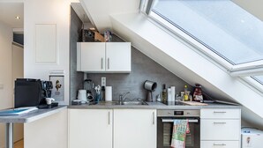 Cozinha moderna com claraboia, eletrodomésticos embutidos e bancada com diversos objetos.