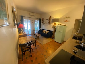 A compact living space with a dining area, a sofa, a refrigerator, and a lamp. - Charming apartment in the heart of Port Grimaud, Parking, Mooring and beach 5mn away (Port Grimaud)