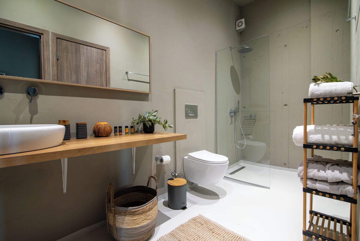 Un baño moderno con tocador de madera, cabina de ducha de vidrio y perchero para toallas.