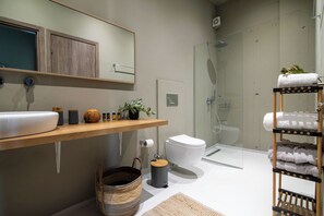 Une salle de bain moderne avec un meuble-lavabo en bois, une cabine de douche en verre et un porte-serviettes.