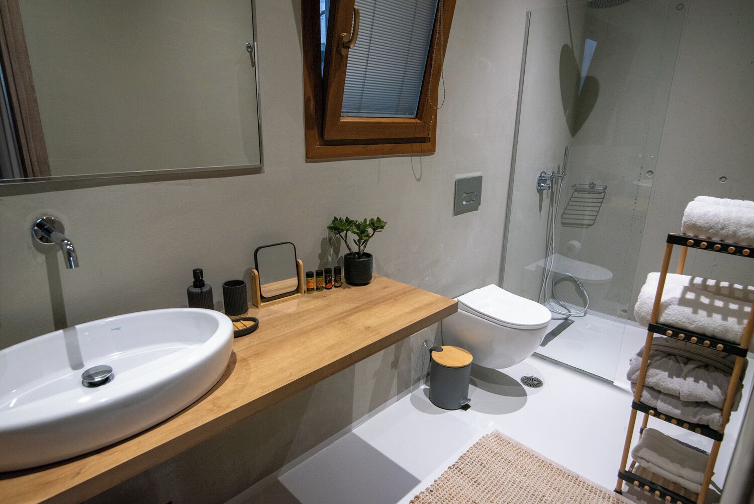 A modern bathroom with a wooden vanity, a large sink, a toilet, and a glass shower enclosure.