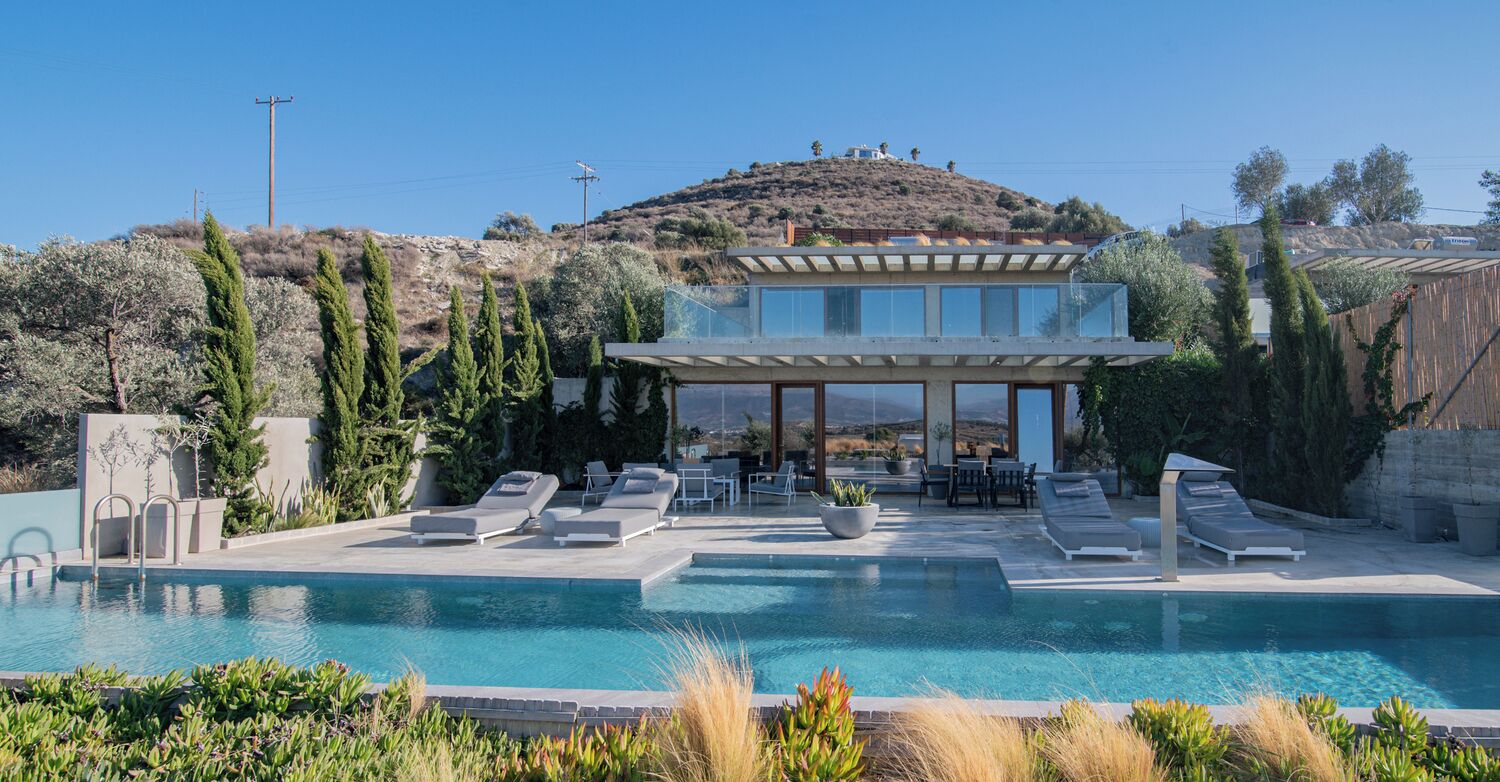 Une villa moderne dotée d’une piscine, d’un espace extérieur aménagé et offrant une vue sur une colline.