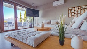 A modern living room with a sofa, a coffee table, and a TV. - Marnos Grand Villa (Faistos)