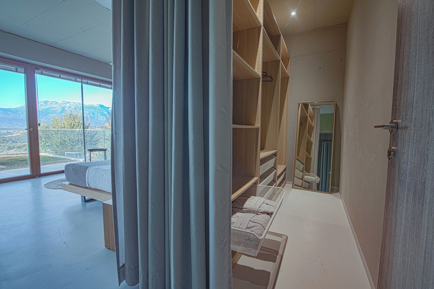 Une chambre moderne dotée d’une grande fenêtre, d’un lit et d’étagères intégrées.