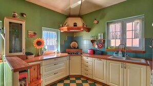 Una cucina con mobili bianchi, un piano di lavoro in legno, un pavimento a scacchi e una finestra con tende.