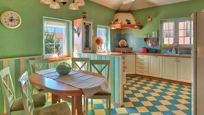 Una cucina con pavimento a scacchi, un tavolo da pranzo con sedie, un lavello e un frigorifero.