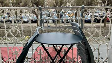 Un balcón con baranda de metal, una mesa negra y un tapete rojo.