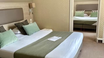 A hotel room with a large bed, a smaller bed, a nightstand, a lamp, and four framed pictures on the wall.