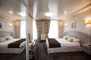 A hotel room with two beds, a desk, a chair, and a mirror. - Marguerite (Dinan)