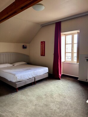 A bedroom with a bed, a window, a radiator, and a ceiling fan. - Marguerite (Dinan)