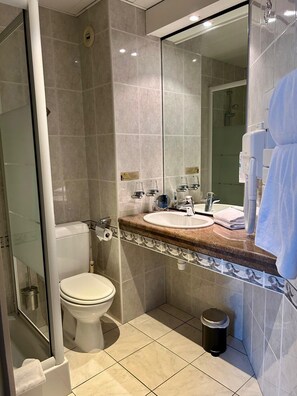 A modern bathroom with a toilet, sink, and shower. - Marguerite (Dinan)