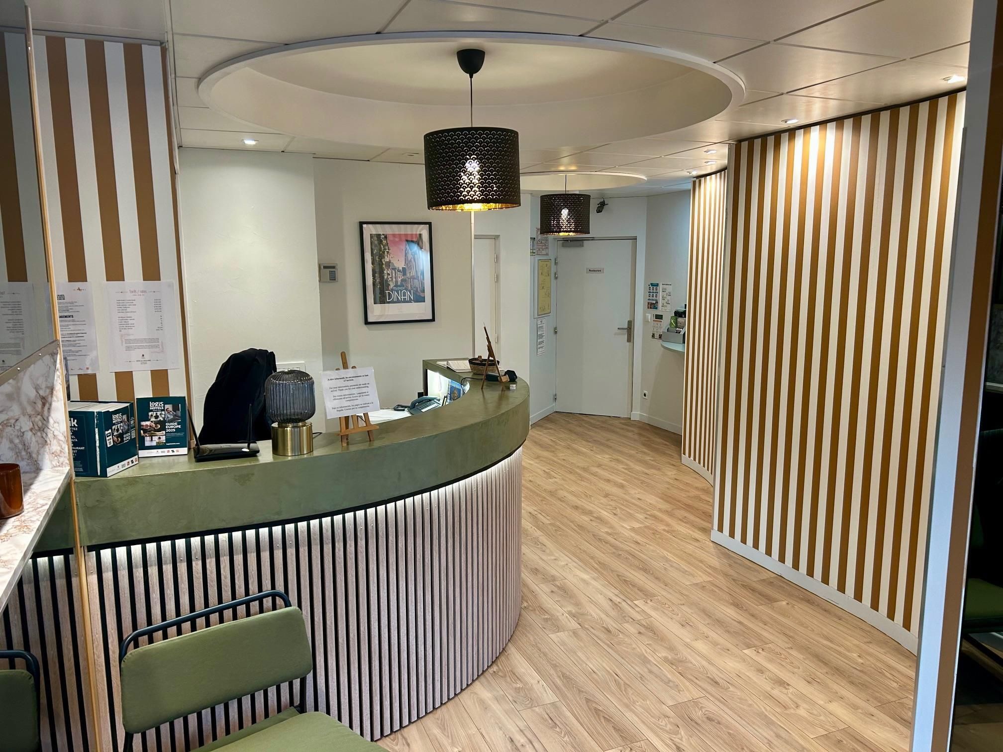 Un mostrador de recepción de diseño curvo, suelo de madera y pared a rayas.