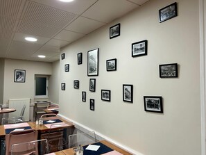 A conference room with tables, chairs, and framed pictures on the walls. - Marguerite (Dinan)