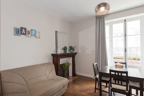 Ein Wohnzimmer mit Sofa, Kamin, Esstisch mit Stühlen und einem Fenster mit Vorhängen.