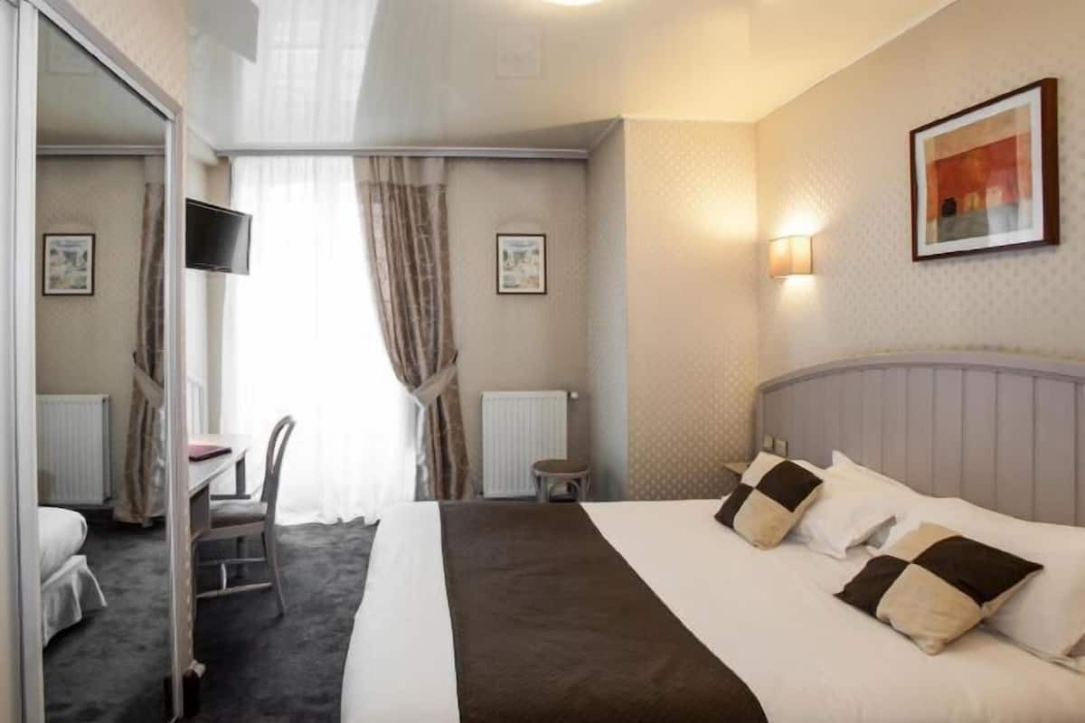 Une chambre d’hôtel avec un lit, un bureau, une chaise, une télévision et un tableau au mur.