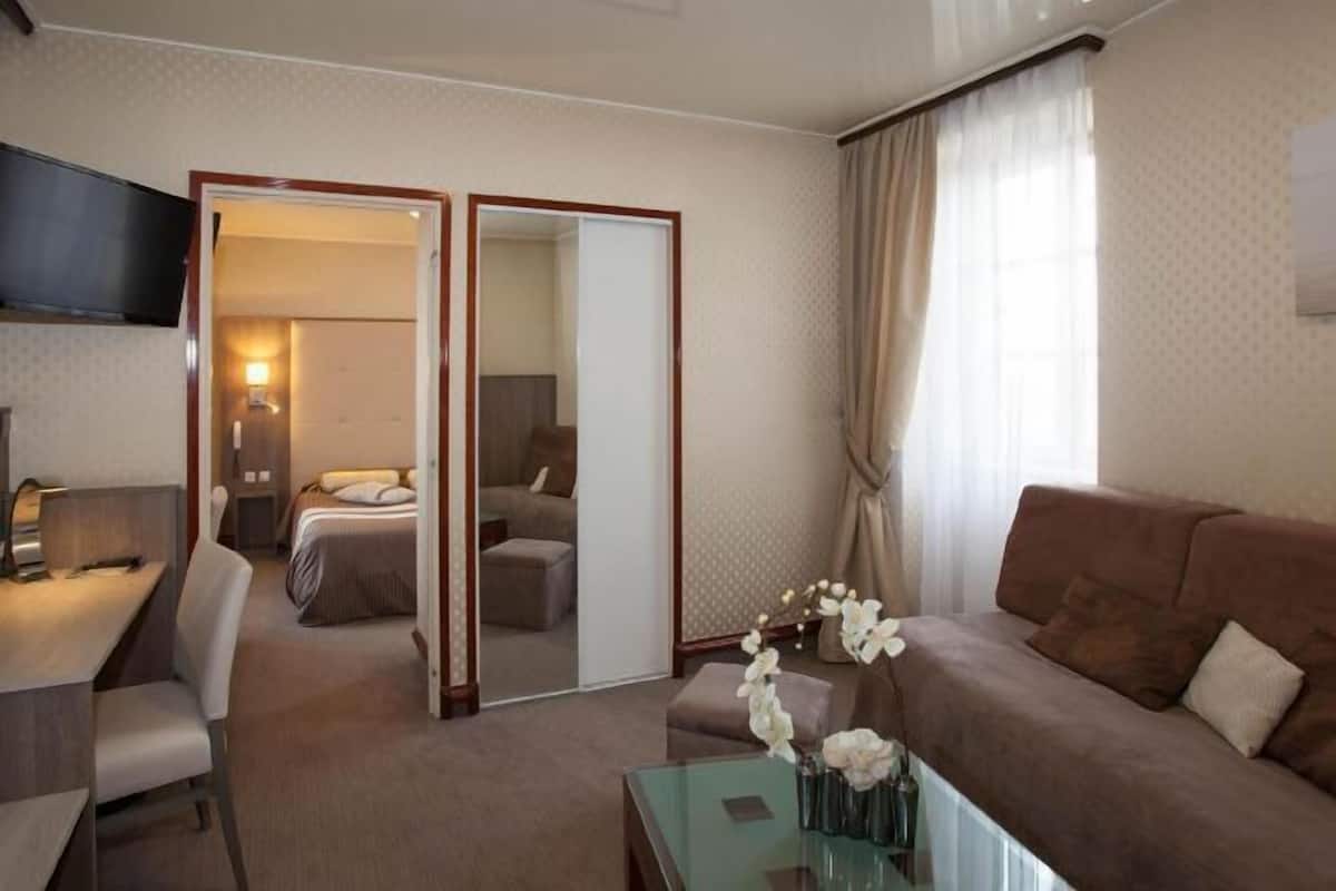 Une chambre d’hôtel comprenant un lit, un canapé, un bureau, un miroir et une table basse en verre.