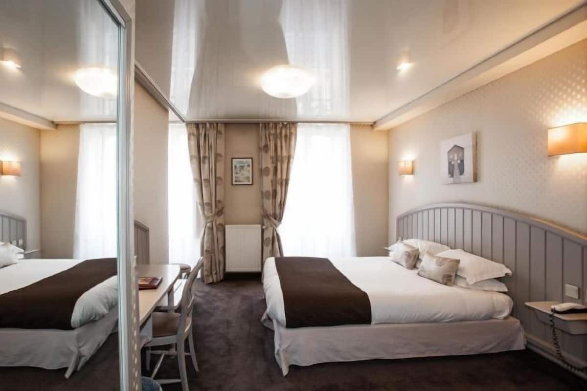 Une chambre d’hôtel avec deux lits, un bureau, une chaise, un téléphone et un radiateur.