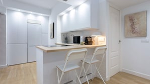 A compact kitchen with white cabinets, a built-in oven, and a small bar area with two white chairs. - Central & Exclusive 2BD Apartment in Cordoba. Hinojo (Córdoba)