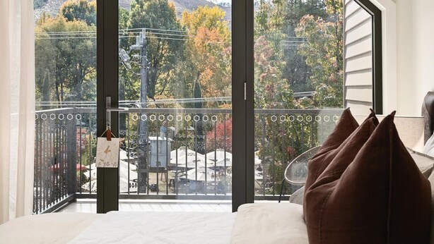 Una camera da letto con un letto grande, vista su un balcone e scorcio panoramico sull'esterno.