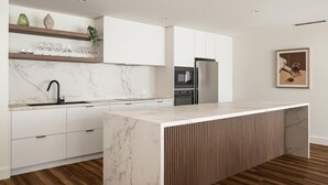 Una cucina moderna con mobili bianchi, un piano di lavoro in marmo e pavimento in legno.