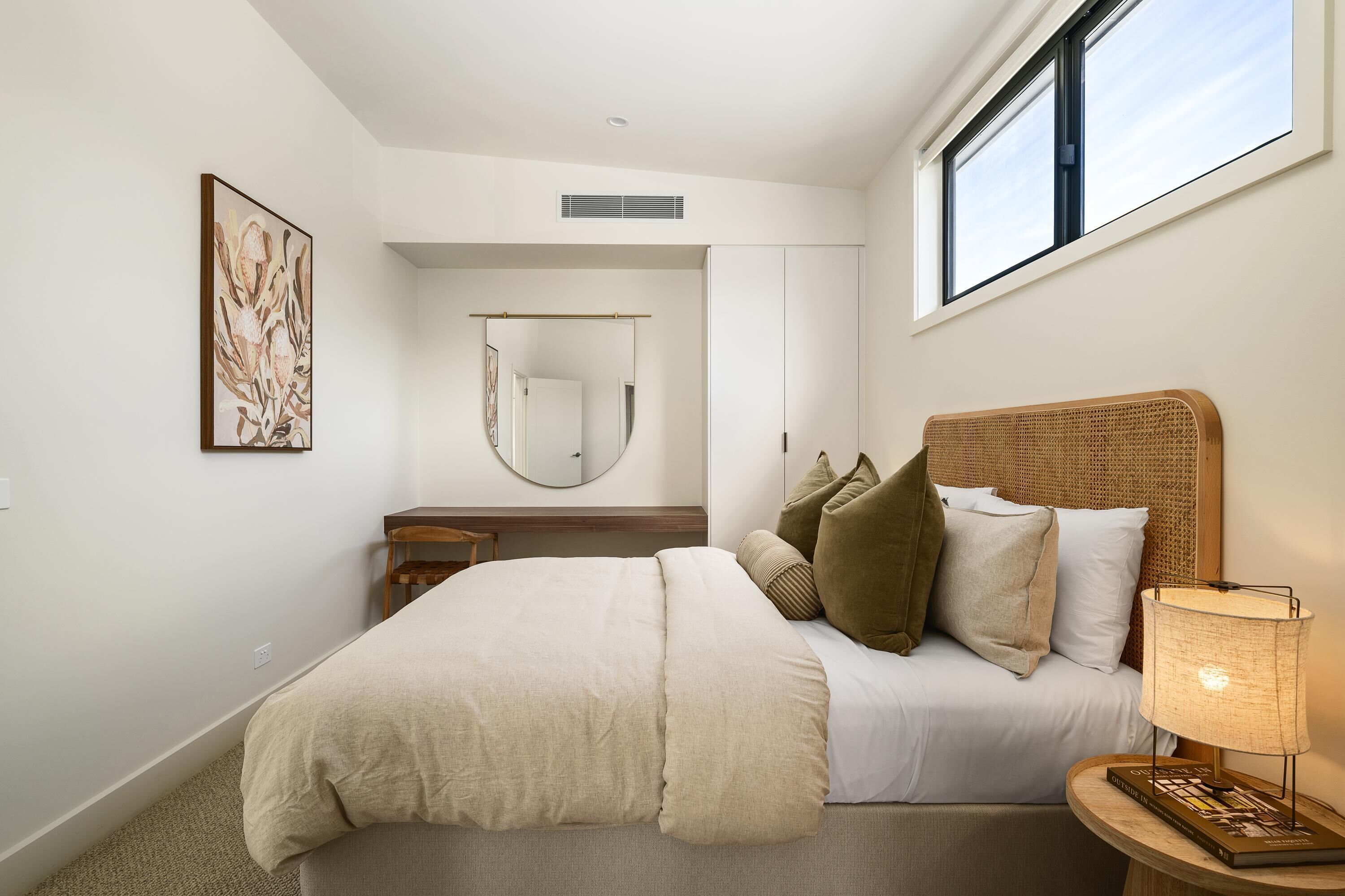 Un dormitorio con cama, lámpara de noche y espejo.