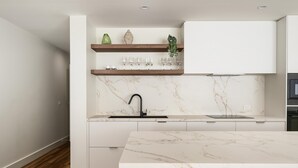 Una cucina moderna con mobili bianchi, una schiena di marmo e un piano di lavoro in legno.