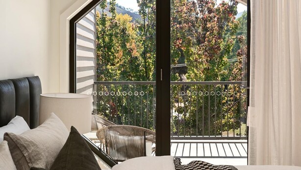 A bedroom with a large bed, a view of trees through a balcony, and a modern design. - Apartment Two - Apartments on Gavan - Welcome to Your Luxurious Getaway at Apartments on Gavan. (Bright)