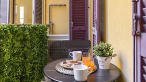 Una mesa con alimentos para el desayuno, una planta en maceta y un vaso de jugo de naranja.