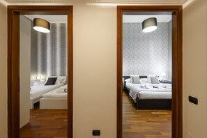 A hallway leading to two bedrooms with wooden flooring, a mirror, and a ceiling light fixture. - Borromei, 11 - Elegance in the center of town (Milan)